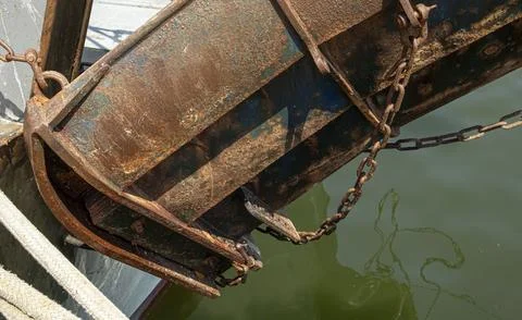 Rusty trawl door hangs over green water from a commercial fishing vessel in.. Stock-Fotos