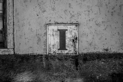 Rusty utility panel with letter I on wall Stock Photos