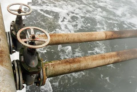 Rusty valves control water flow in an old treatment plant, showcasing the ess Stock Photos