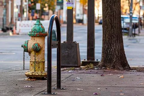 A rusty, vintage fire hydrant on side of a road on the sidewalk Stock Photos