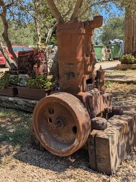Rusty vintage industrial engine displayed outdoors among trees and garden 스톡 사진