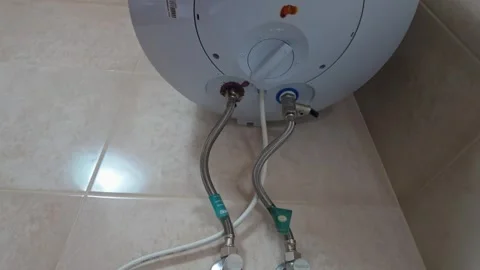 Rusty wall-mounted water heater leaking around pipe connections and valve Stock Footage 337507500
