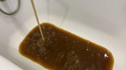Rusty water flows into the white tub from the tap. Stock Footage 152018503