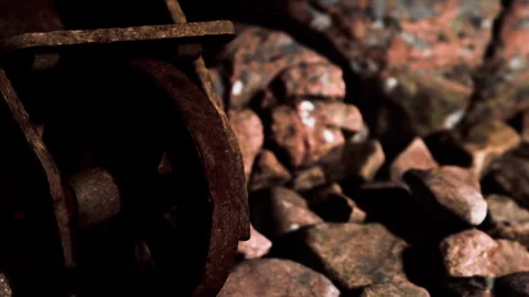 Rusty wheel resting on rocky ground near a mining site during late afternoon Stock Footage 339475033