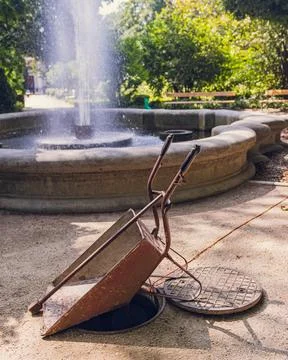 Rusty Wheelbarrow Over Open Manhole in Park Photos
