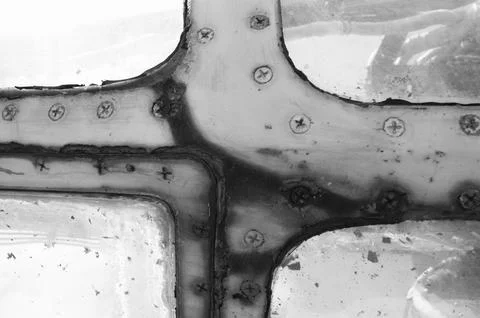 Rusty window frame of an old airplane with screws. Black and white photo. Stock Photos
