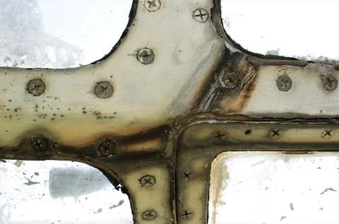 Rusty window frame of an old airplane with screws. Stock Photos