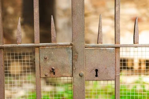 Rusty wrought iron gate with antique lock detail in historic stone village Stock Photos