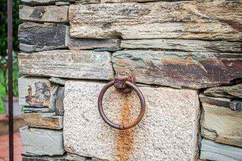 Rusty wrought iron ring set in a stone wall to hold animals in a rustic house Stock Photos
