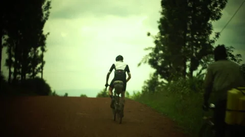 Rwanda - 3 September 2018: cyclists pedal in a dirt climb Stock Footage 138630340