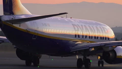Ryanair Boeing 737 fuselage glowing at sunset while taxiing for takeoff Stock Footage 337800399