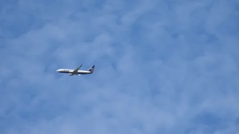 A Ryanair plane flying in a bright blue sky with white clouds in the background. Stock Footage 277946780