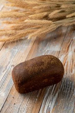 Rye borodinsky bread loaf with coriander on old wooden table with wheat spike Stock Photos