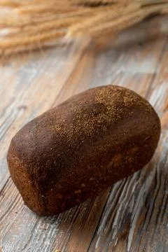 Rye borodinsky bread loaf with coriander on old wooden table with wheat spike Stock Photos