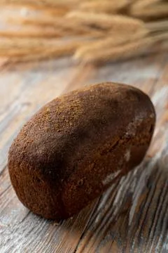 Rye borodinsky bread loaf with coriander on old wooden table with wheat spike Stock Photos