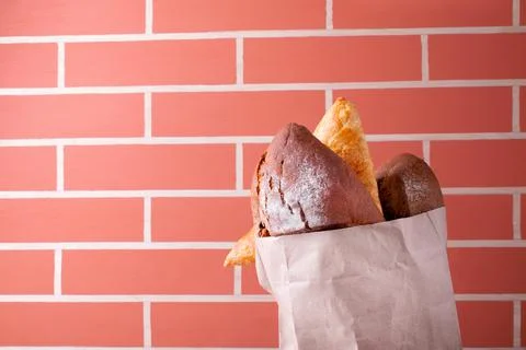 Rye bread and wheat bun in craft paper bag by the brick wall Stock Photos