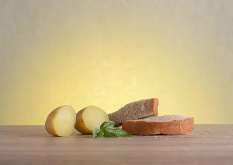 Rye bread, basil and boiled potatoes on a wooden table at sunrise. Stock Photos