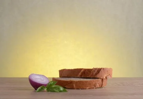 Rye bread, basil and red bulb onion on a wooden table at sunrise. Stock Photos