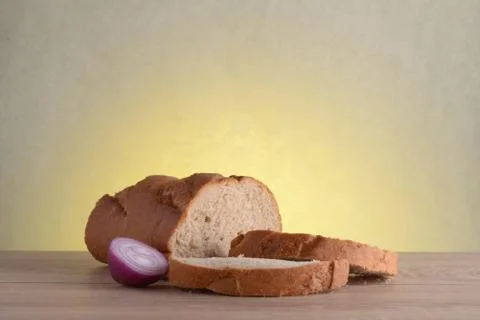 Rye bread, basil and red bulb onion on a wooden table at sunrise. Stock Photos