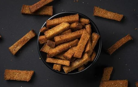 Rye bread croutons on black background, top view Stock-Fotos