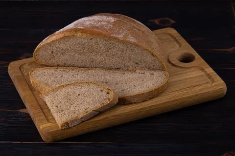 Rye bread on a cutting board on a dark background. Sliced bread Stock Photos
