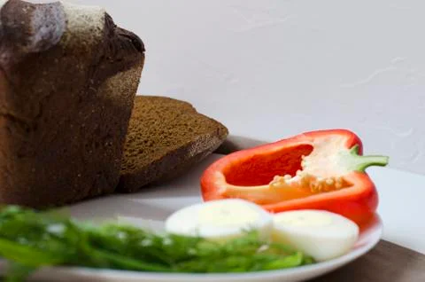 Rye bread, egg and pepper on a white background Stock Photos