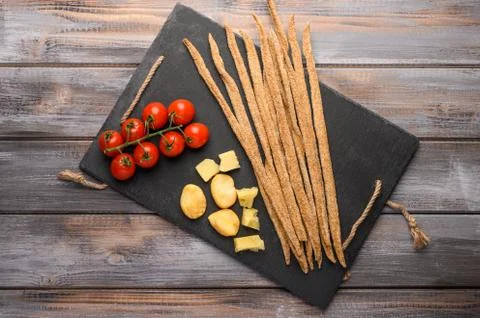 Rye bread grissini, cherry tomatoes, cheese and greens on a black cast iron Stock Photos
