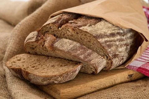 Rye bread inside paper package on wooden board Stock Photos