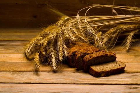 Rye bread, a loaf, ears of corn on a background of wooden boards Stock Photos