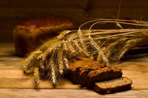 Rye bread, a loaf, ears of corn on a background of wooden boards Stock Photos
