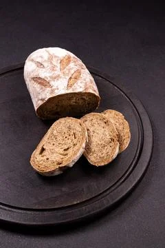 Rye bread loaf with slices on dark board Stock Photos