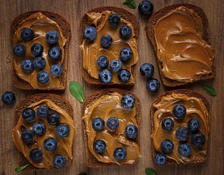 Rye bread with peanut paste and fresh blueberries, top view, no people 스톡 사진