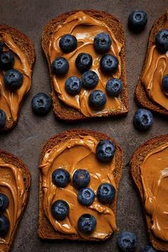 Rye bread with peanut paste and fresh blueberries, top view, no people 스톡 사진