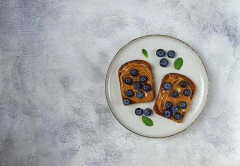 Rye bread with peanut paste and fresh blueberries, top view, no people 스톡 사진