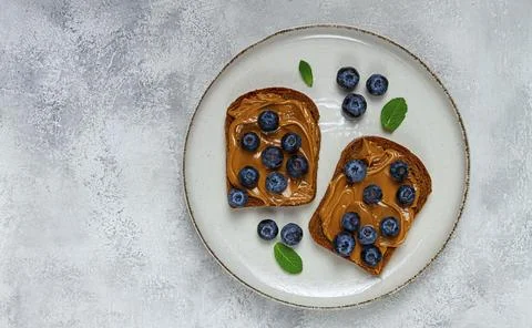 Rye bread with peanut paste and fresh blueberries, top view, no people 스톡 사진