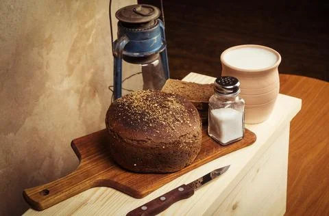 Rye bread with salt on a cutting board and a pot of milk Stock Photos