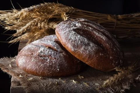 Rye bread with spikelets on burlap and wood Foto stock
