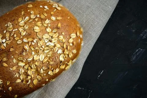 Rye bread sprinkled with oatmeal on a background of gray linen fabric Foto stock