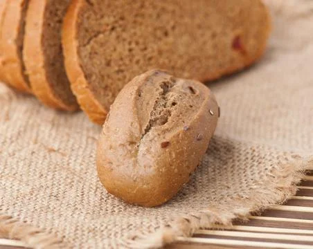 Rye bun and slices of bread on the table Stock Photos