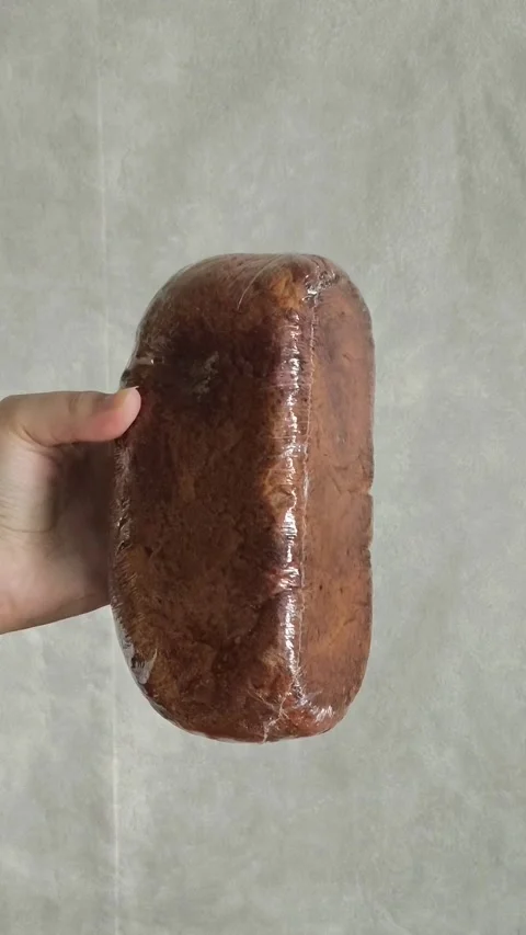 Rye loaf of bread in transparent packaging in a womans hand. Bread products made Stock-Footage 325774483