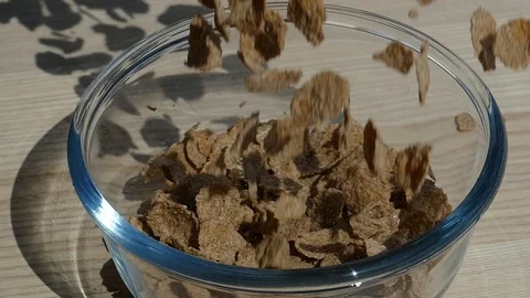 Rye muesli falling into empty transparent glass bowl, slow motion Stock Footage 96976729