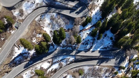 S curve switchback stack retaining wall guardrail light snow dusting cars climb Stock Footage 345962843