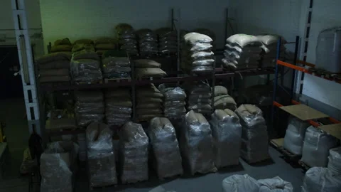 Sacks of roasted coffee beans lie on shelves of warehouse Video stock 306597437