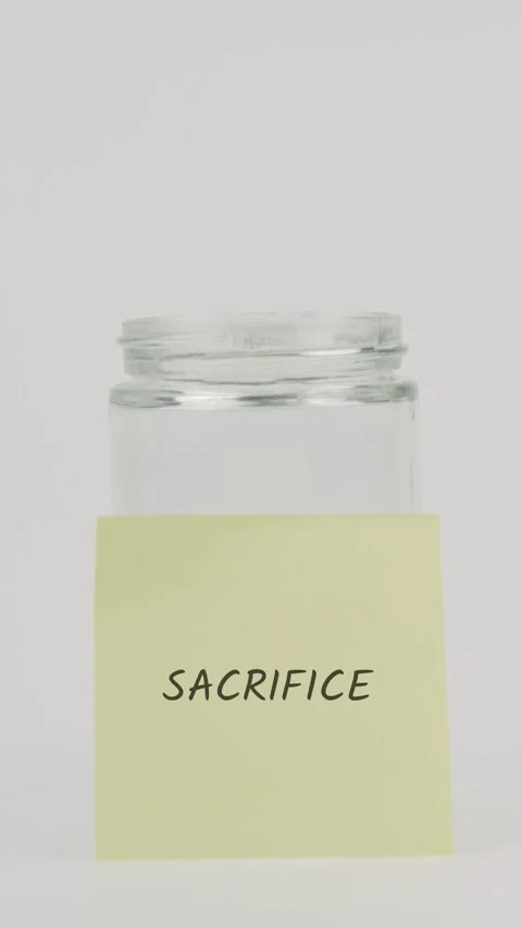 Sacrifice text or word on yellow sticky note attached to glass jar with hand Stock Footage 311783345