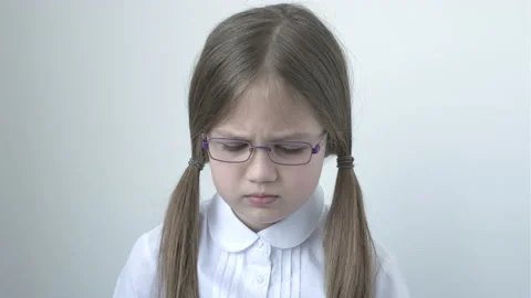 Sad 9 years old school girl in glasses and uniform on gray background Stock Footage 201888808