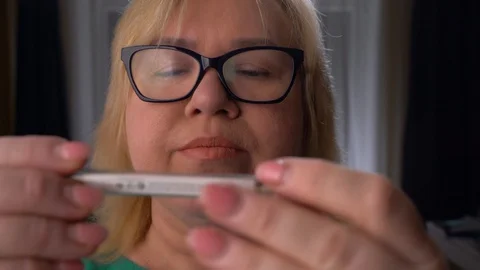 Sad adult Woman Looks At A Thermometer Measuring Temperature Home Stock Footage 128643781