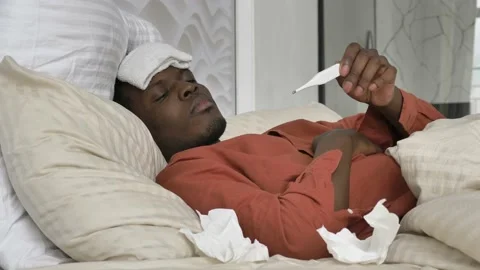 Sad African-American man with patch checks temperature Stock Footage 153939750
