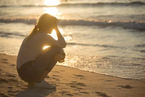 Sad and alone young woman at the beach. Stock Photos