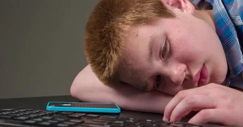 Sad and depressed boy at computer keyboard with cell phone 4k 動画素材 51388552