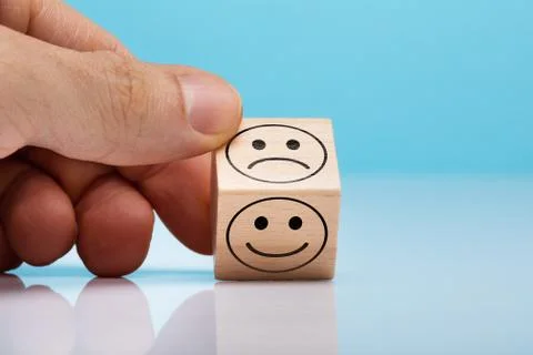 Sad And Happy Face Wooden Block Holding By Person's Hand Stock Photos